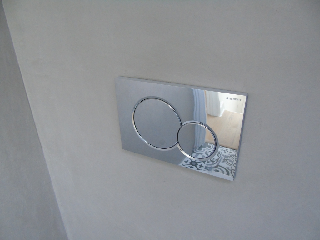 Wall mounted toilet flush on a seamless microcement wall